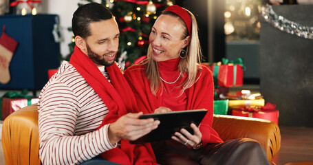 Christmas, tablet and smile with couple on sofa for online shopping, xmas discount and gift research. Holiday season, festive deals and relax with man and woman in living room of home for happiness