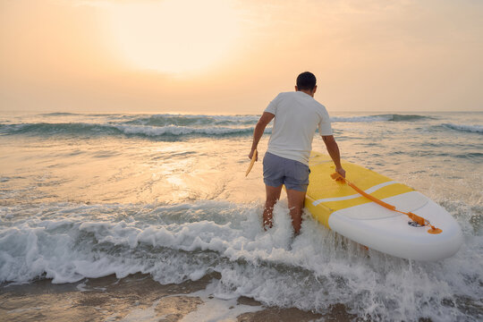 Man enjoying paddleboarding at sunset on ocean waves
