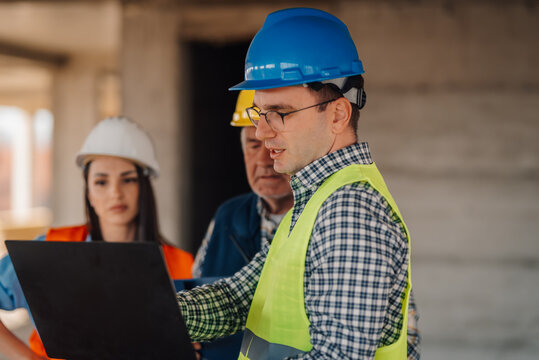 Engineers using laptop discussing project on construction site