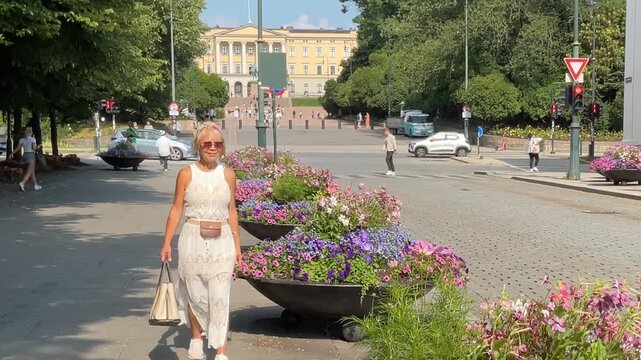 Woman walking the city center streets in Oslo, Norway.  Footage from Karl Johan street with the royal castle in the background.