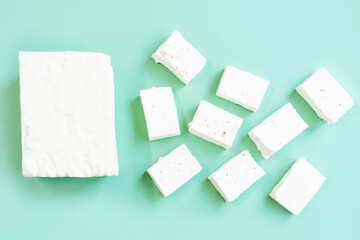 Whole tofu and sliced on green background, top view.