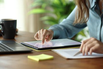 Office worker scrolling on tablet checking statistics on document