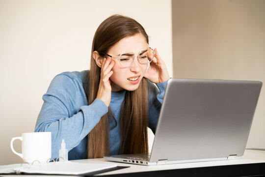 Young woman with glasses looking at laptop screen squinting, hands touching temples. Digital eye strain eye fatigue issues related to excessive gadget use the impact of screens on vision digital era.