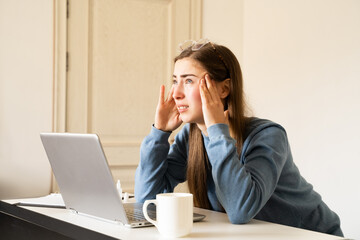 Young woman looking up feeling headache touching temples after laptop work. Digital eye strain eye fatigue issues related to excessive computer use the impact of screens on vision digital era.