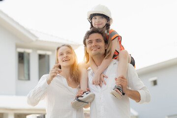 Family fun time with mom and dad at home. Couple playing with their daughter and creating happy childhood memories. Dad carrying his daughter on his shoulders and standing next to mom.