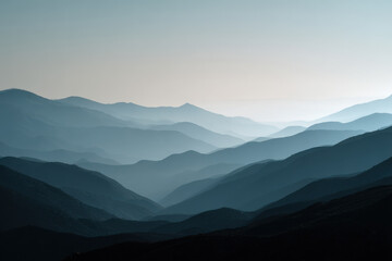 Fototapeta premium Misty mountain landscape with layered hills, soft blue tones, and serene atmosphere evokes tranquility and peace