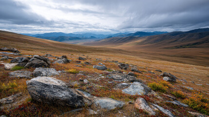 Fototapeta premium Vast landscape with rocky terrain, rolling hills, and dramatic clouds. scene evokes sense of tranquility and natural beauty