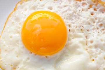 Fried egg on white dish close up