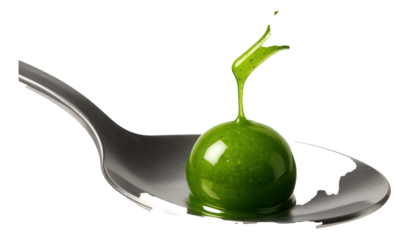 A stream of bright green sauce drops from a pipette, forming a perfect sphere on a spoon.