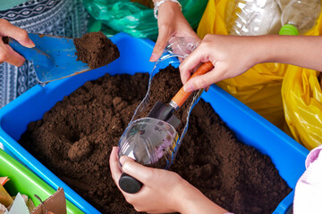 Hands Using Scoop To Add Soil To Recycled Plastic Bottle Creating Sustainable Planter