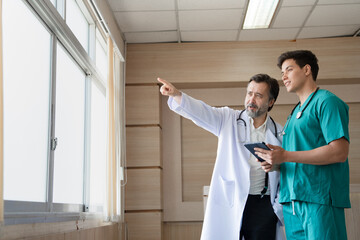 Major Caucasian man doctor with medical student use tablet computer working at hospital	