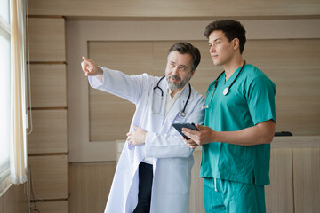 Major Caucasian man doctor with medical student use tablet computer working at hospital	