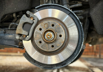 Car brake disc with grey caliper. Brake disc and wheel hub part close-up. The removed car wheel. Blurred background. Car Details. The tire fitting process. 
