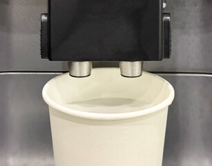Making coffee by coffee machine into paper cup, latte coffee coming out from an automated...