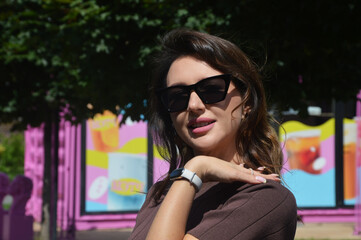 Portrait of young elegant stylish woman in brown dress and sunglasses on city street.