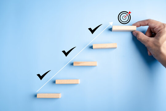 Business growth success and achievement with hand arranging wooden steps and check marks, goal setting, progress tracking, and personal development.