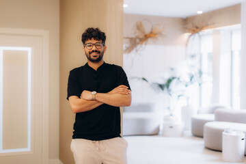 Confident businessman smiling with crossed arms in modern office lobby