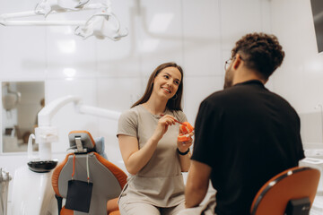 Dentist showing teeth model to patient in modern clinic