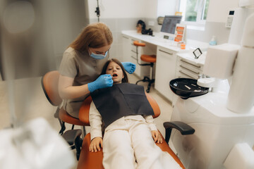 Dentist examining teeth of little girl in dental clinic