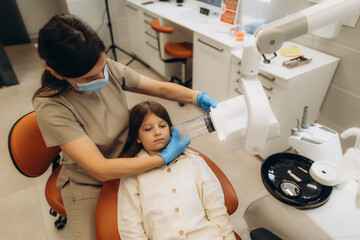 Dentist positioning x-ray machine near patient's head in dental clinic