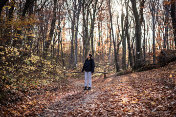 Young hiker exploring autumn forest trail at sunset
