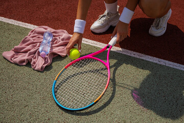 Close-Up of Female Tennis Player Preparing on Outdoor Court with Racket, Ball, and Hydration...