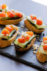 close up stock photo of greek-style crostini topped with olive paste, cucumber slices, cherry tomatoes, and feta cheese