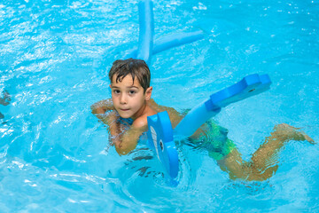 Child swimming with float in a blue pool during summer vacation
