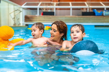Mother having fun with children in swimming pool