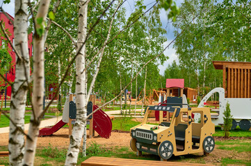 colorful playground features vibrant slide and wooden vehicle surrounded by lush trees, inviting...