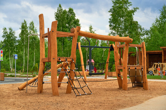 wooden playground equipment with climbing ropes and slides under lush green trees, perfect for outdoor activities and children's physical development in natural play settings