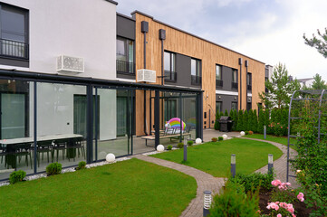 modern residential complex features sleek glass-enclosed patio, lush greenery, contemporary...