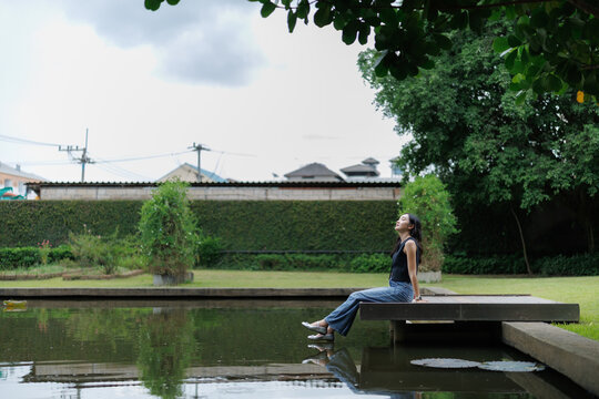 Young woman relaxing by the pond in a peaceful garden