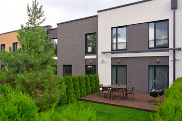 modern townhouse exterior with lush garden features sleek contemporary architecture, wooden deck, outdoor furniture, and vibrant greenery for urban living, relaxation, and style.