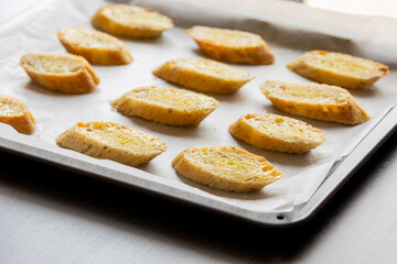  slices of bread neatly arranged in a tray, ready to be baked into crostini