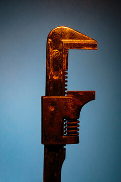 A metal adjustable pipe wrench on a blue background