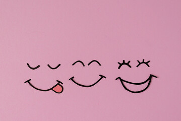 The joyful emotion of love and success is represented by three smiling faces on a soft pink background. Emotions, joy, happiness