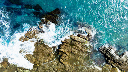 Crashing Sea Against Textured Rock Layers
