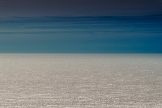 The ocean surface, silver sea and blue sky on the horizon. 