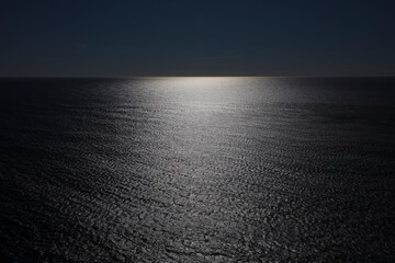 The vast ocean and reflections of light on the water surface, black and white image.
