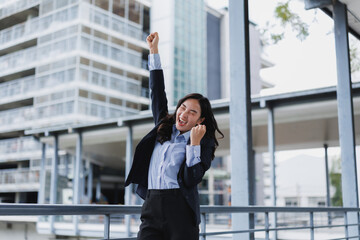 Excited businesswoman celebrating triumph with raised arms in city