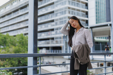Tired businesswoman touching hair on modern city footbridge