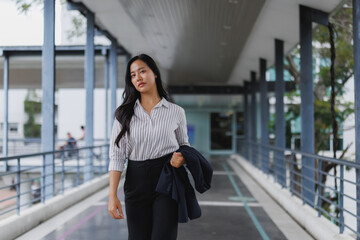 Young asian businesswoman walking in modern office building corridor