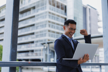 Happy manager reading good news on his laptop and celebrating success outdoor