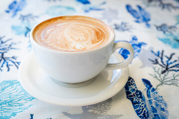 A top-down shot of a delicious cappuccino with detailed latte art, presented in a white cup on a...