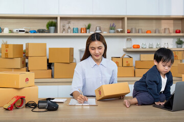 Sell Online: A mother organizing her e-commerce business with her child beside her