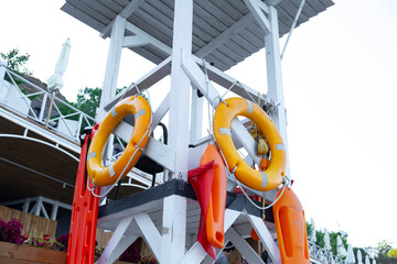 A white wooden lifeguard tower stands ready with bright yellow lifebuoys and orange rescue cans...