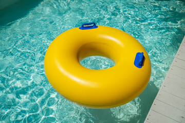 Bright yellow inflatable ring floating in a clear blue lazy river surrounded by lush greenery. A...