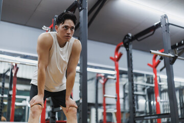 Young athlete resting after intense workout in modern gym