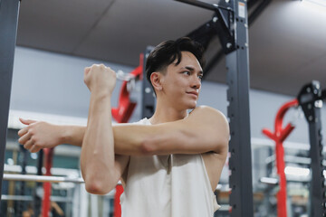 Young sportsman stretching arms before training in gym